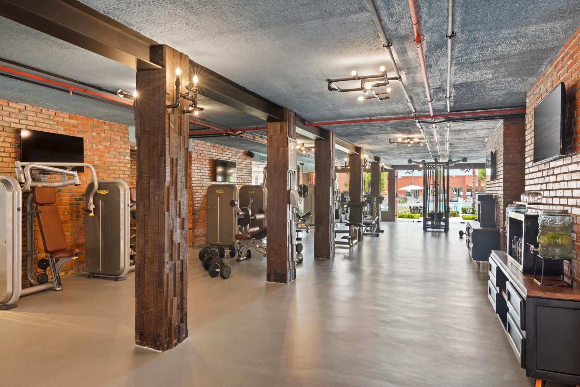 Savoy Le Grand Hotel Marrakech Marrakesz Zewnętrze zdjęcie The photo shows a modern gym interior with a spacious layout. It features a polished concrete floor and exposed brick walls, giving it a contemporary yet industrial feel. There are various pieces of gym equipment, including weight machines and free w