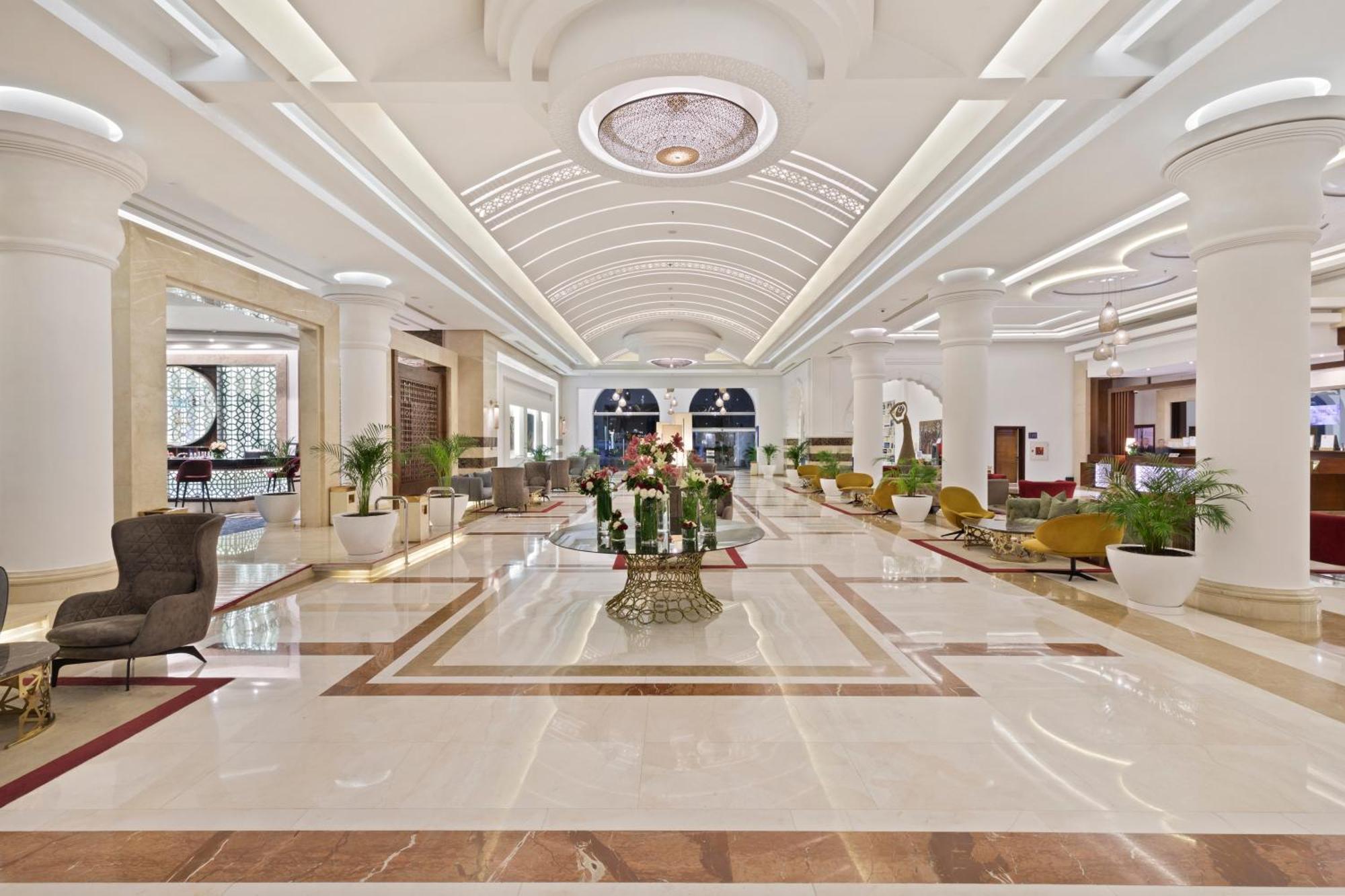 Savoy Le Grand Hotel Marrakech Marrakesz Zewnętrze zdjęcie The photo shows an elegant hotel lobby. It features a spacious and bright area with high ceilings and well-designed architecture. The floor is polished marble, showcasing a luxurious pattern. There are stylish seating arrangements with various chairs